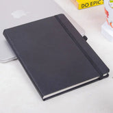 Black Primo A5 Diary with elastic closure on desk, ideal for productivity planning with 80GSM pages and pen loop for office organization.