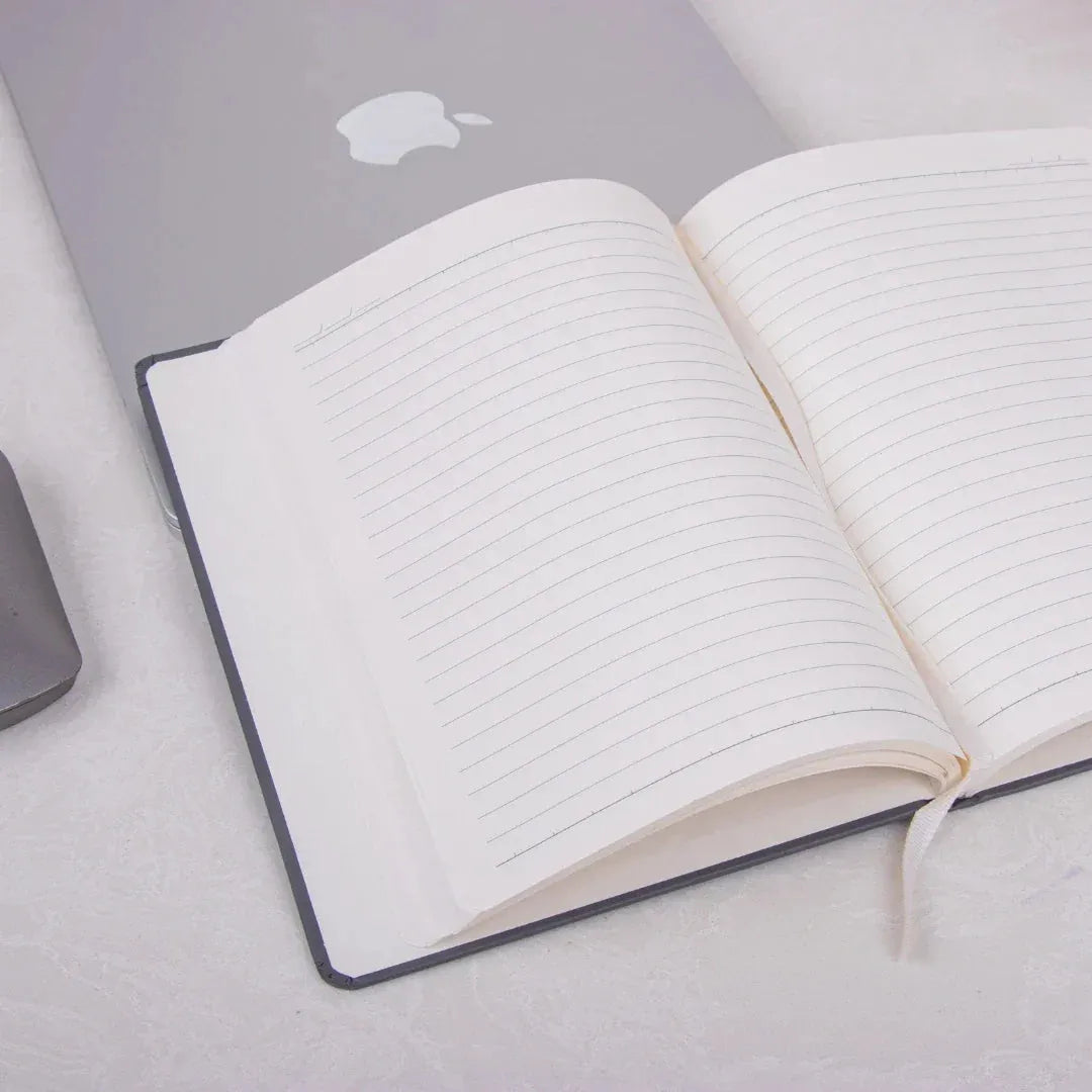 Storyteller’s Journal Personalized Diary with lined pages open on a desk beside a laptop. Ideal for planning workdays and tracking goals.