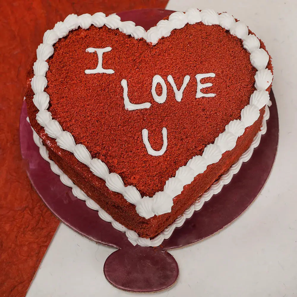 Delicious red velvet heart shape cake with white cream border and cherry filling, perfect for gifting on special occasions.