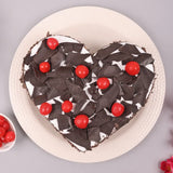 Top view of Heart Shape Black Forest Cake - Lovers Day Cakes Online, decorated with red cherries and dark chocolate flakes.