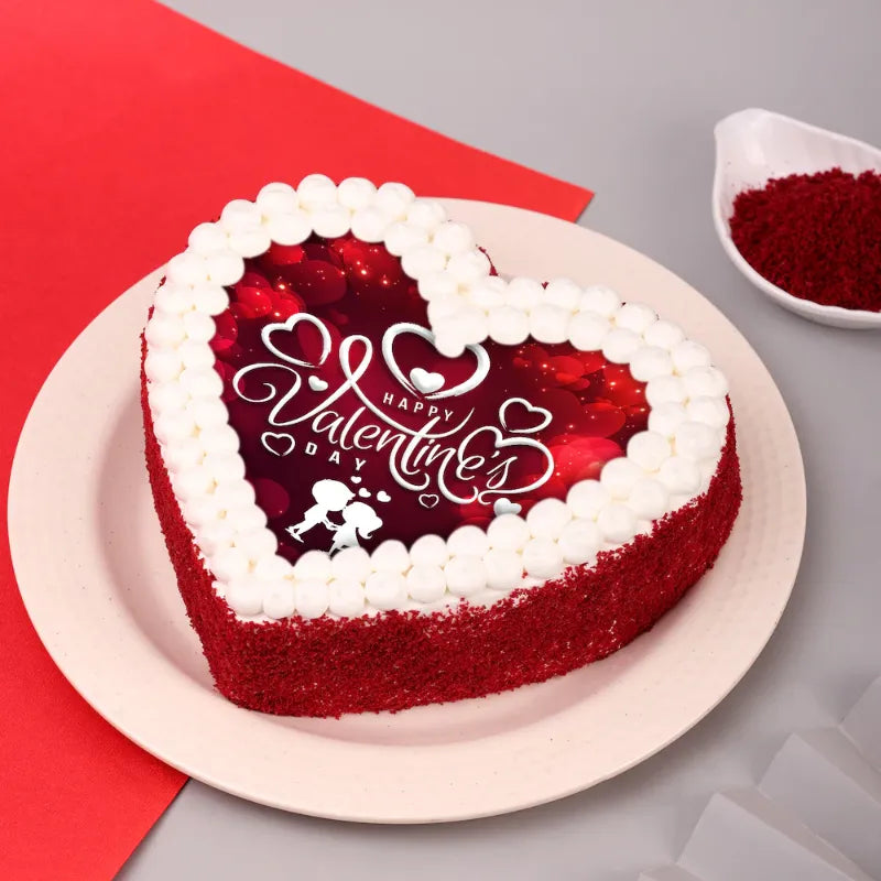 Heart-shaped Red Velvet Valentines Poster Cake with red crumbs and printed 'Happy Valentine's Day' topper, ideal for romantic celebrations.