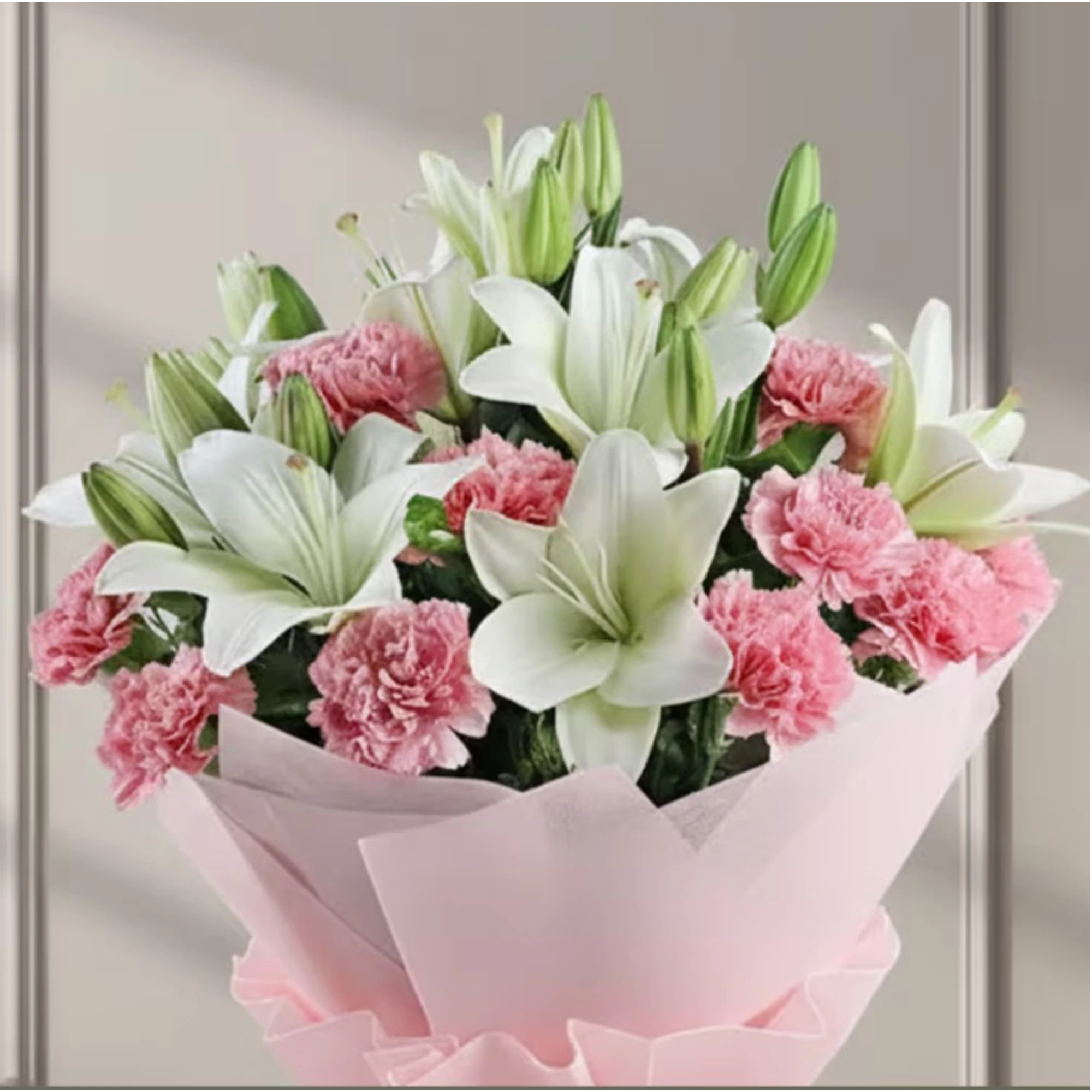 Hand holding a bouquet of white lilies and pink carnations wrapped in pink paper