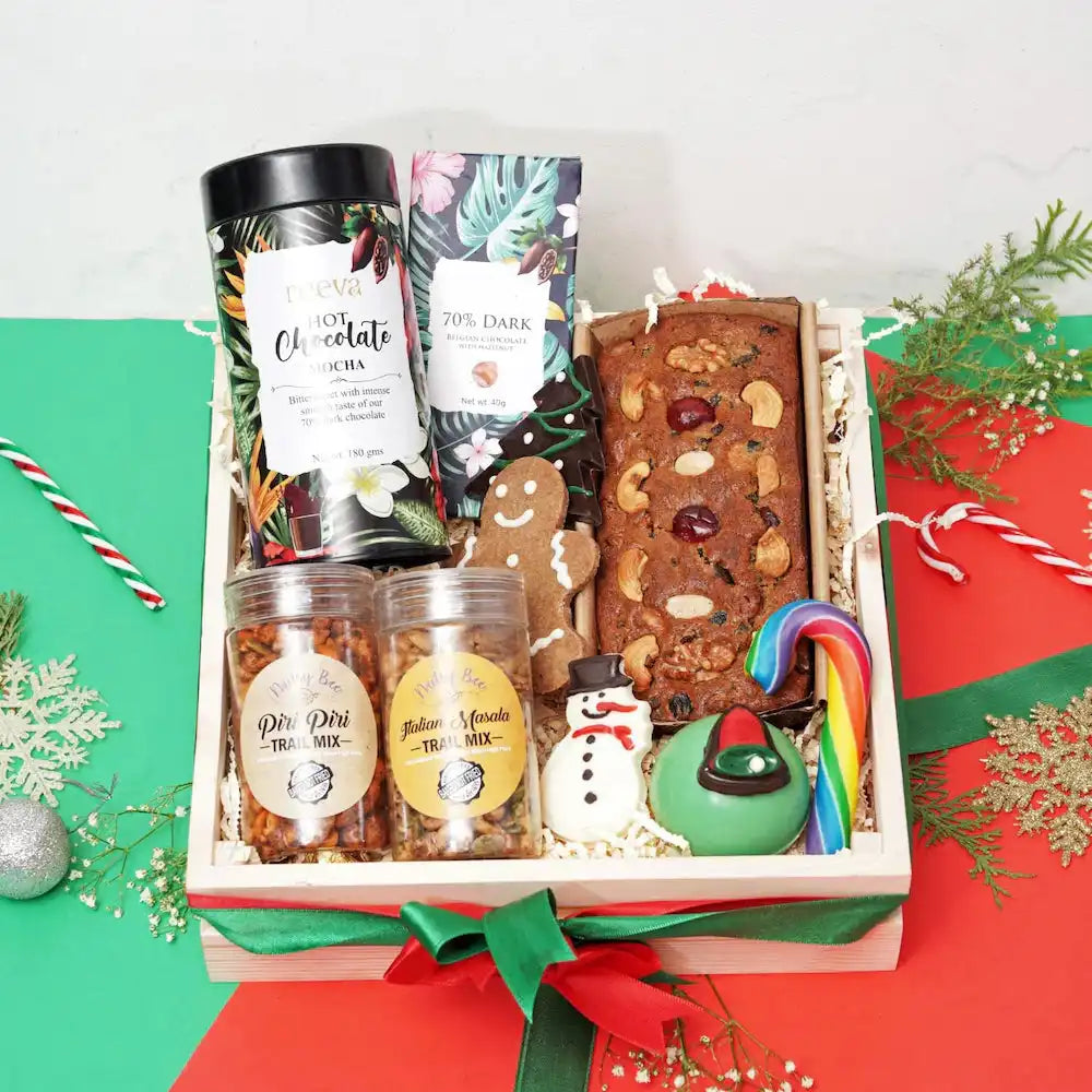 Gourmet Christmas Treat Treasury Hamper with assorted snacks including trail mix, tea cake, candy cane, and holiday-themed cookies.