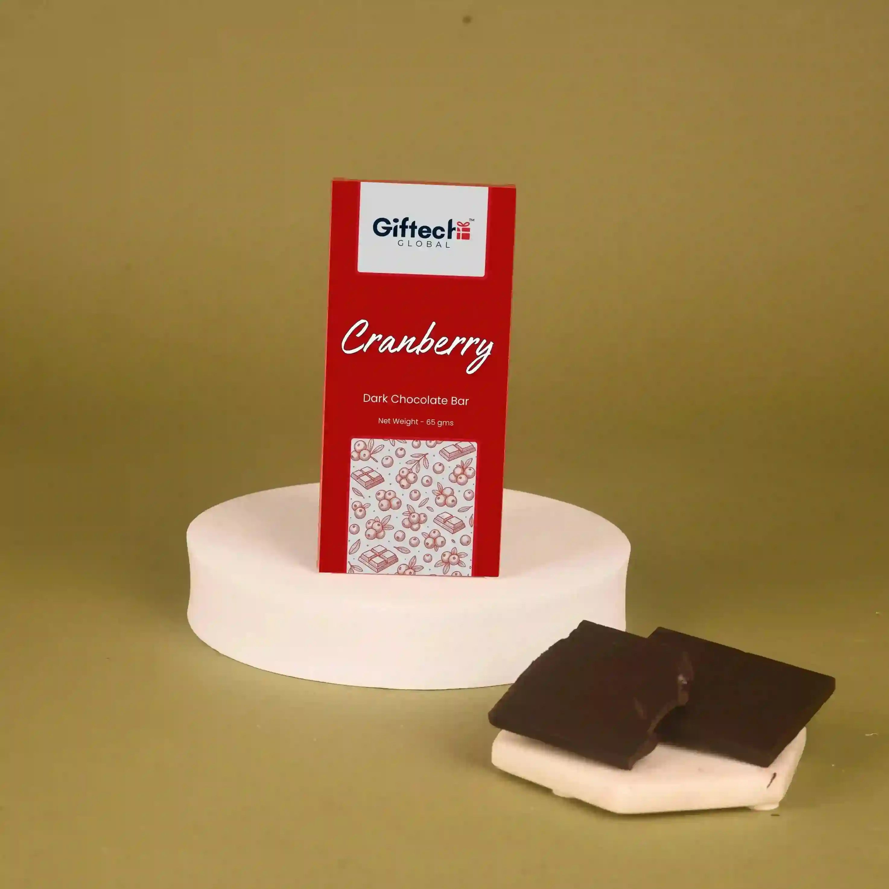 Red Giftech cranberry dark chocolate bar packaging on a white stand with two chocolate bars in front on a green background