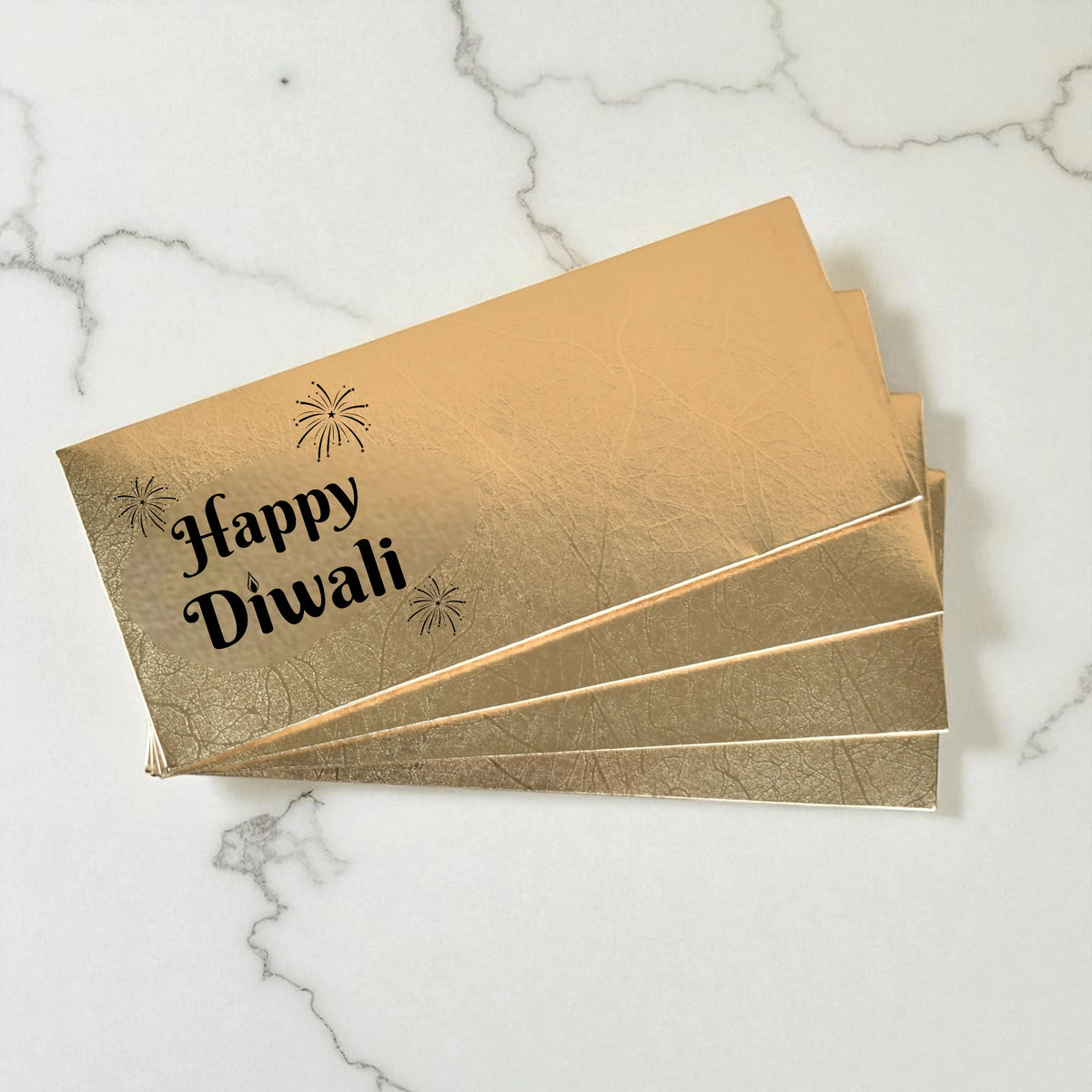 Gold envelopes with 'Happy Diwali' text on a marble surface