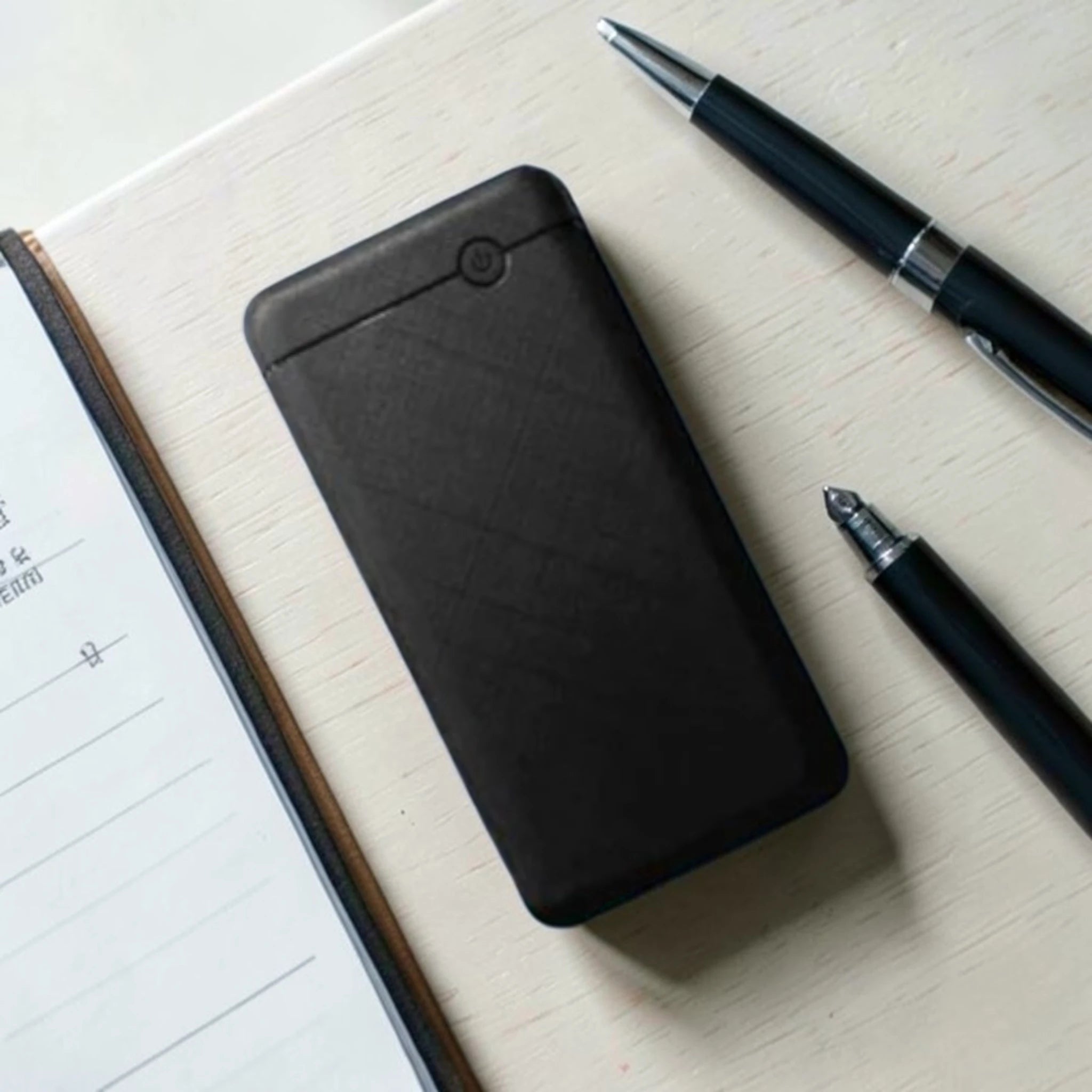 Black power bank with power button on white desk