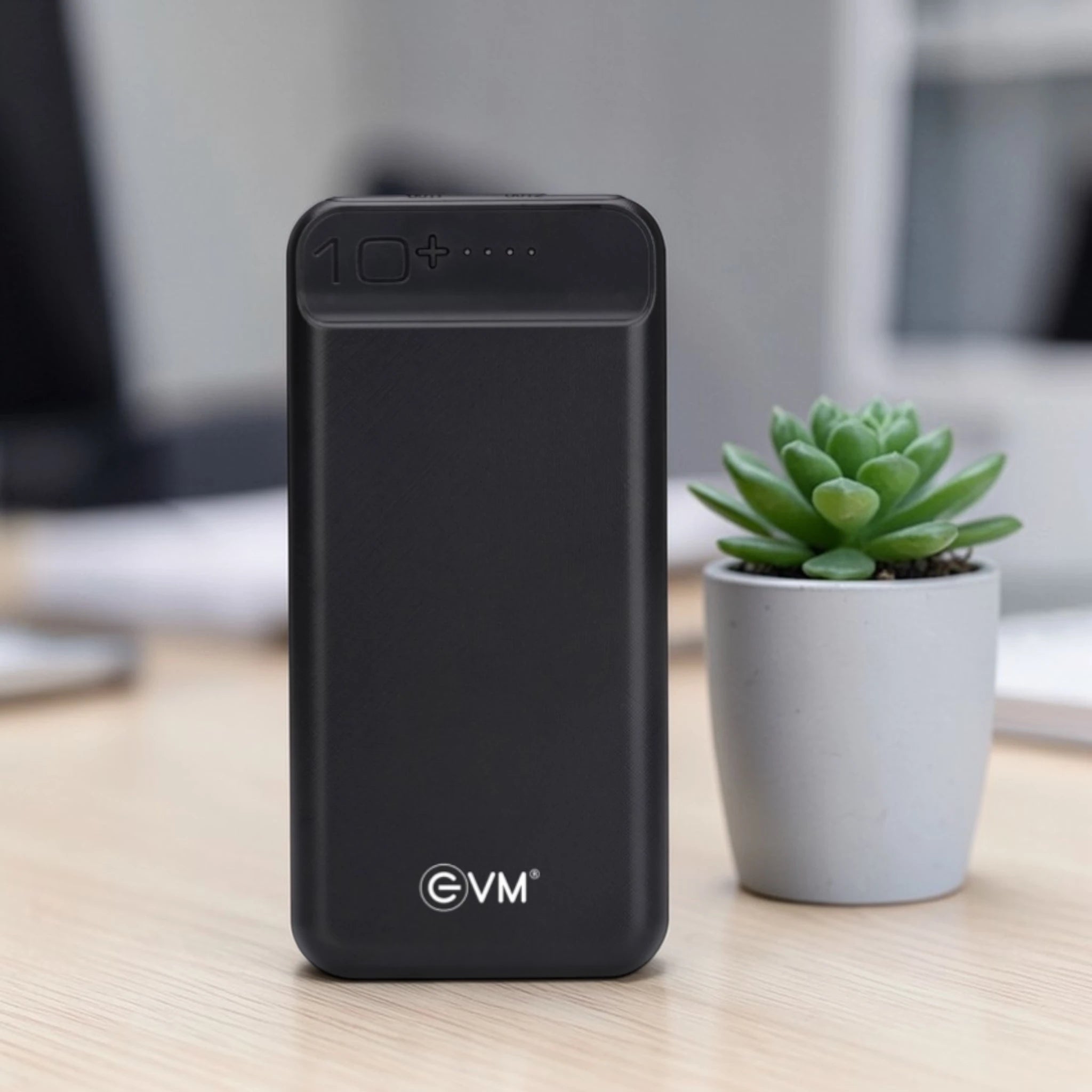 Black power bank with 'EVM' branding on a desk with a plant in the background