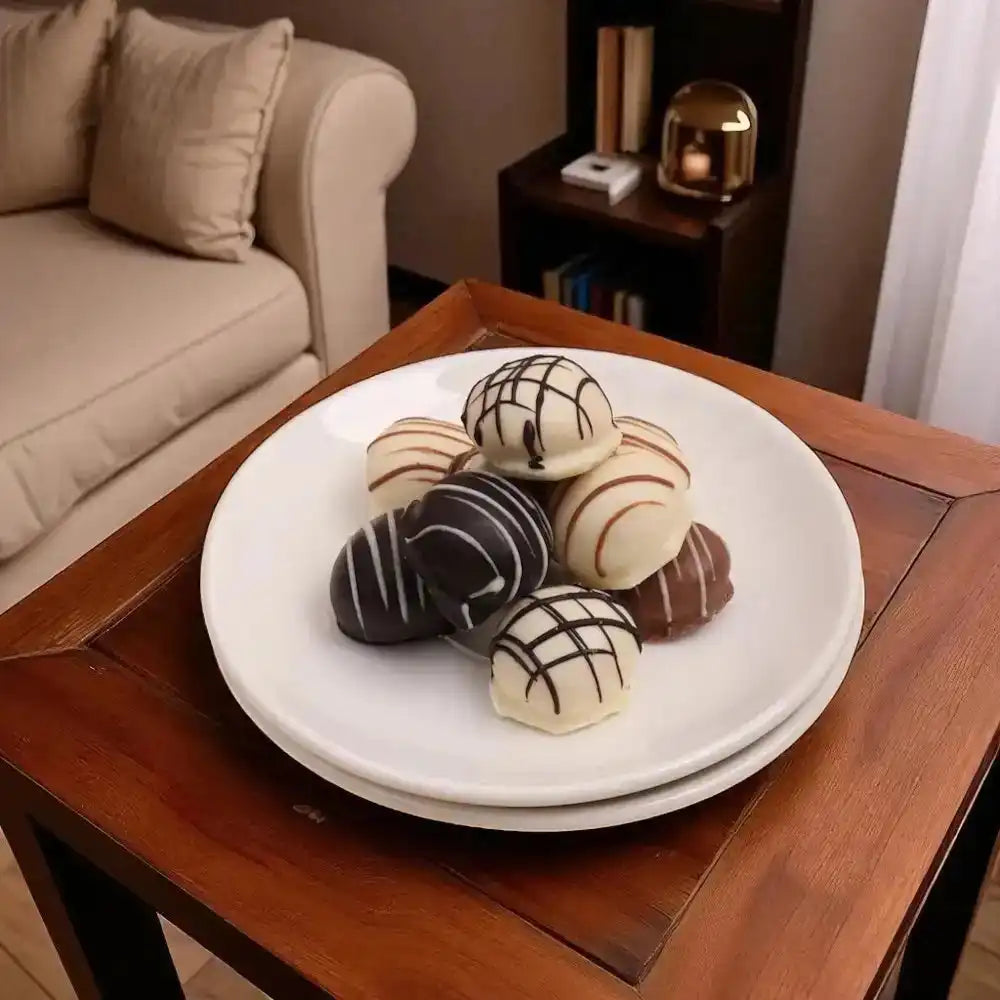 Assorted white and dark chocolate truffles from the Delight Chocolate Box - Gourmet Gift, elegantly plated on a wooden side table.