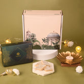 Decorative setup with a box, candles, and a small structure on a green background