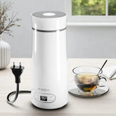 White electric thermos with digital display on a table next to a cup of tea.