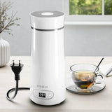 White electric thermos with digital display on a table next to a cup of tea.