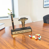 Pen holder with caduceus symbol on a desk with pills and a blurred office background