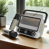 Portable audio device with two microphones on a wooden surface near a window.