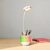 Desk lamp with a colorful base and holder for stationery on a wooden surface.