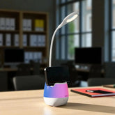 Multifunctional device with a lamp, phone holder, and colorful base on a desk.