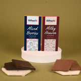 Mixed Berries Milky Chocolate Duo 65g featuring two chocolate bars—Mixed Berries and Milky Heaven—on a display with chocolate pieces. Ideal for gifting.