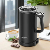 Black electric milk frother on a table with coffee and snacks, featuring the Xtech brand.