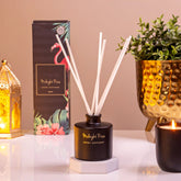 Diffuser with reeds, packaging, plant, and candle on a table