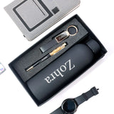 Gift set with black water bottle, pen, keychain, and watch in a box labeled 'Zohra'.