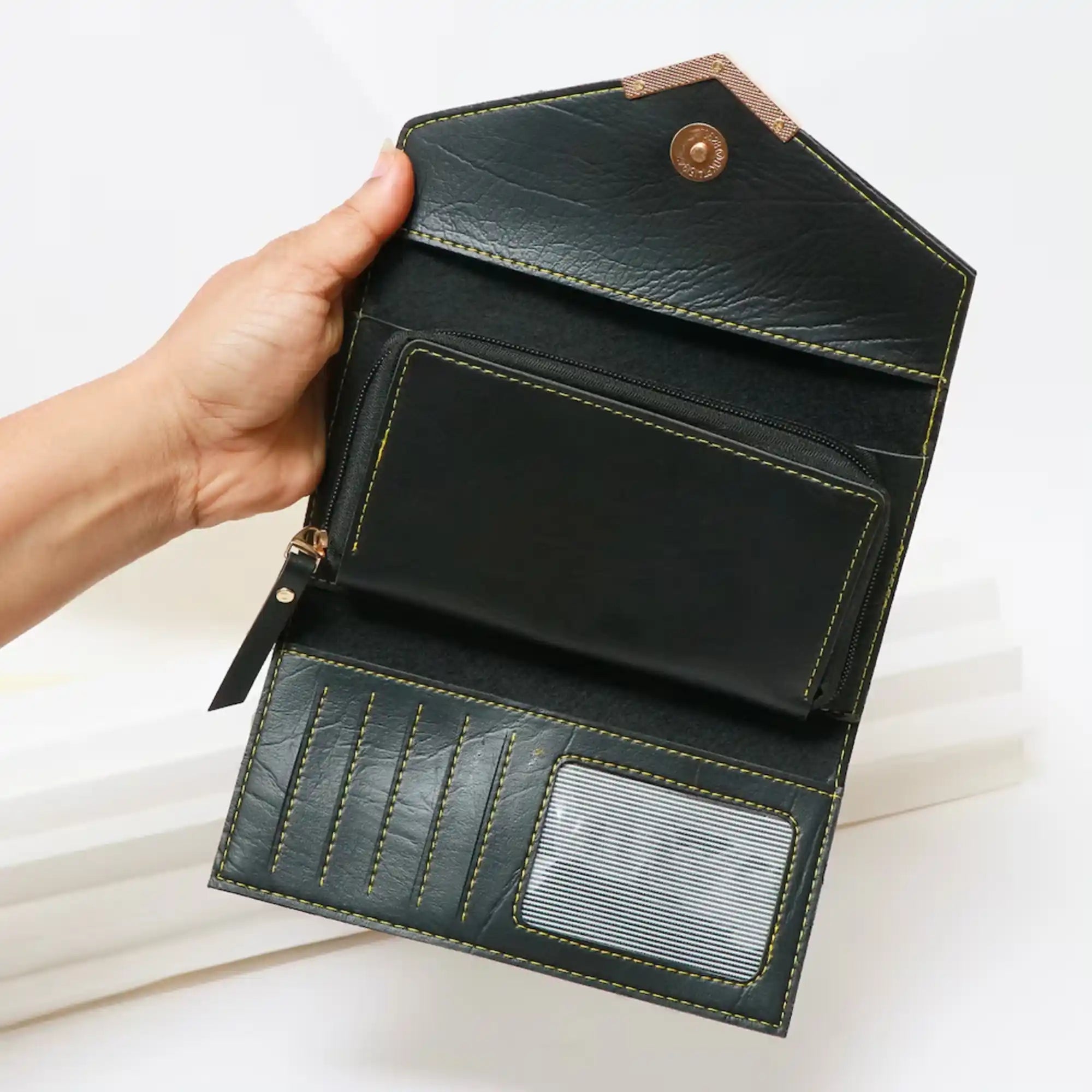 Hand holding a black leather wallet with a white background