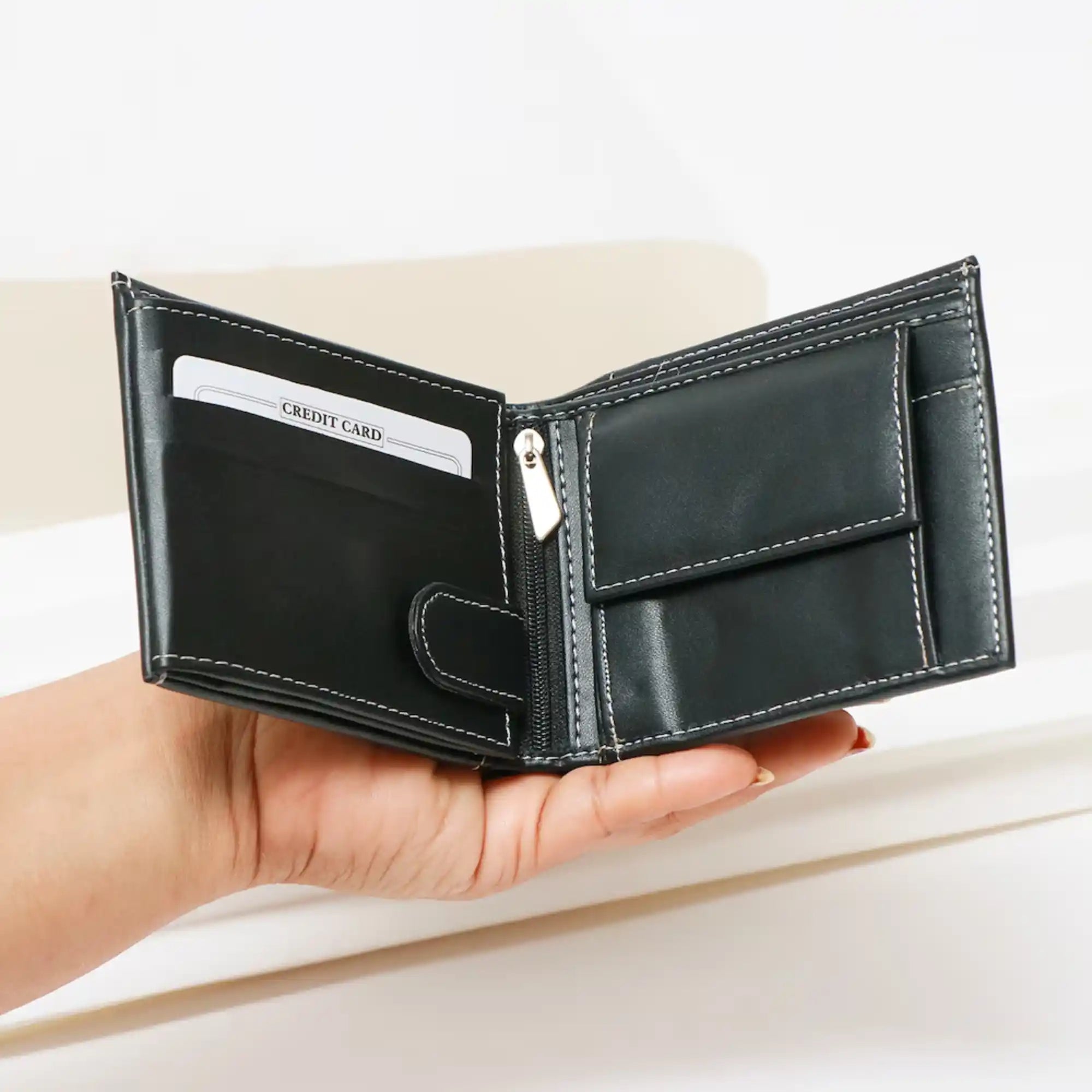 Black leather wallet held in a hand with a white card inside, on a light background