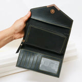 Hand holding a black leather wallet with a white background