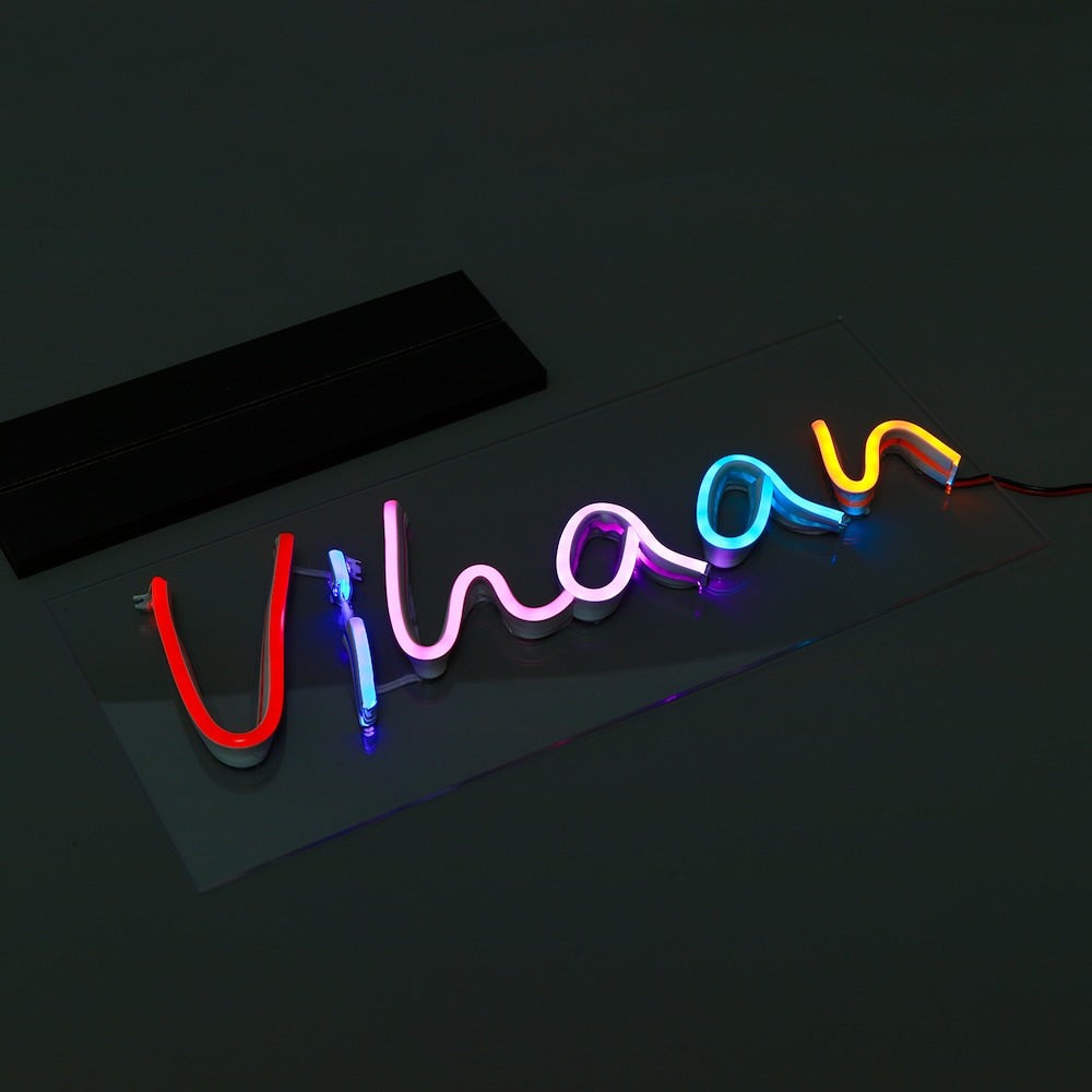 Custom LED Neon Sign with name 'Vihaan' in vibrant red, pink, blue, and yellow tones, perfect for tabletop display in home or office.