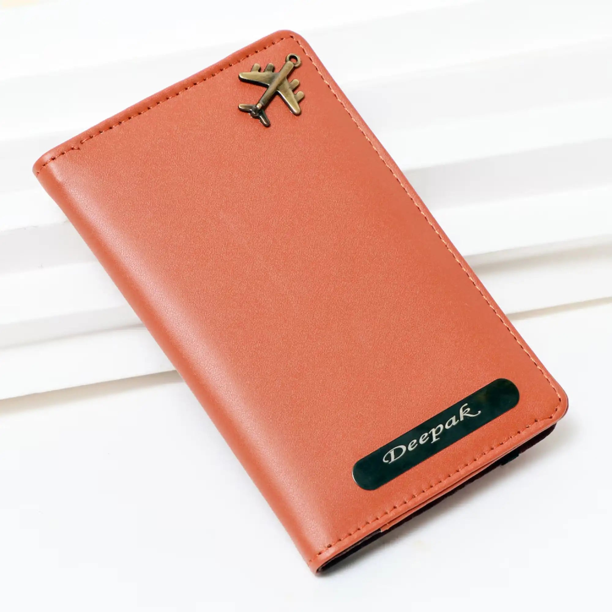 Brown leather passport holder with airplane emblem on a white background