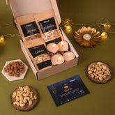 Gift set with candles, nuts, and a Diwali card on a green surface with decorative lights.