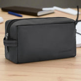 Black toiletry bag on a wooden surface with a blurred background