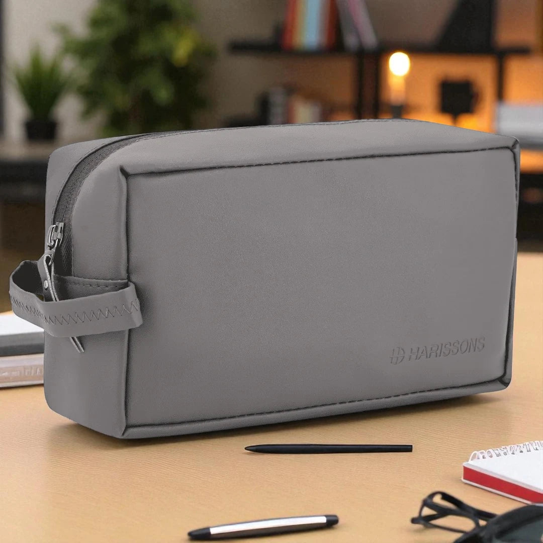 Gray toiletry bag on a desk with stationery items