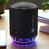 Black Portronics Bluetooth speaker on a wooden surface