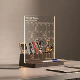 Transparent monthly planner with stationery items on a wooden stand against a neutral background