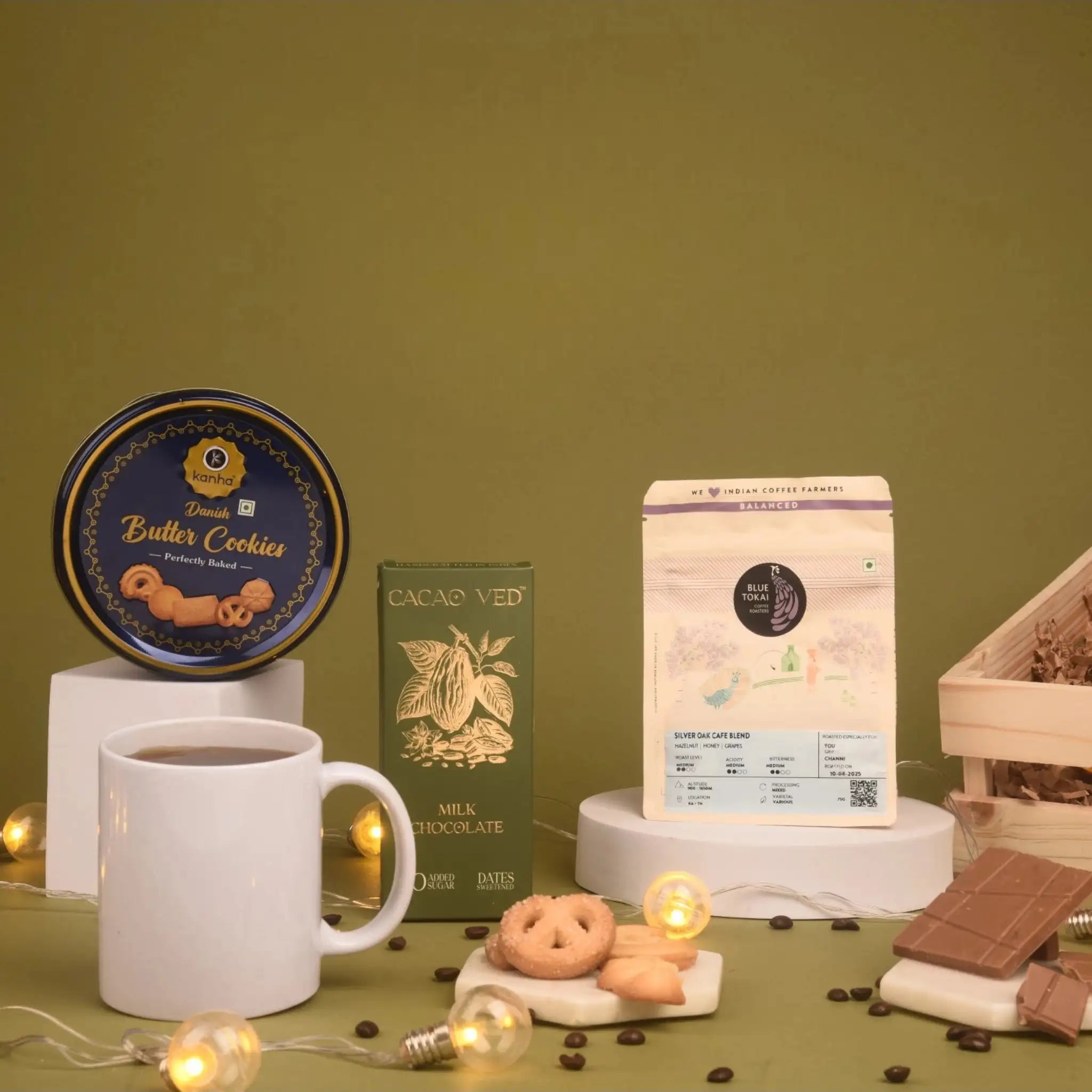 The Caffeine Couture Hamper featuring Blue Tokai coffee, Danish butter cookies, Cacao Ved milk chocolate, and a white mug on a festive setup.