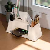 Desk organizer with phone charging station, tissue dispenser, pens, and markers on a wooden surface.