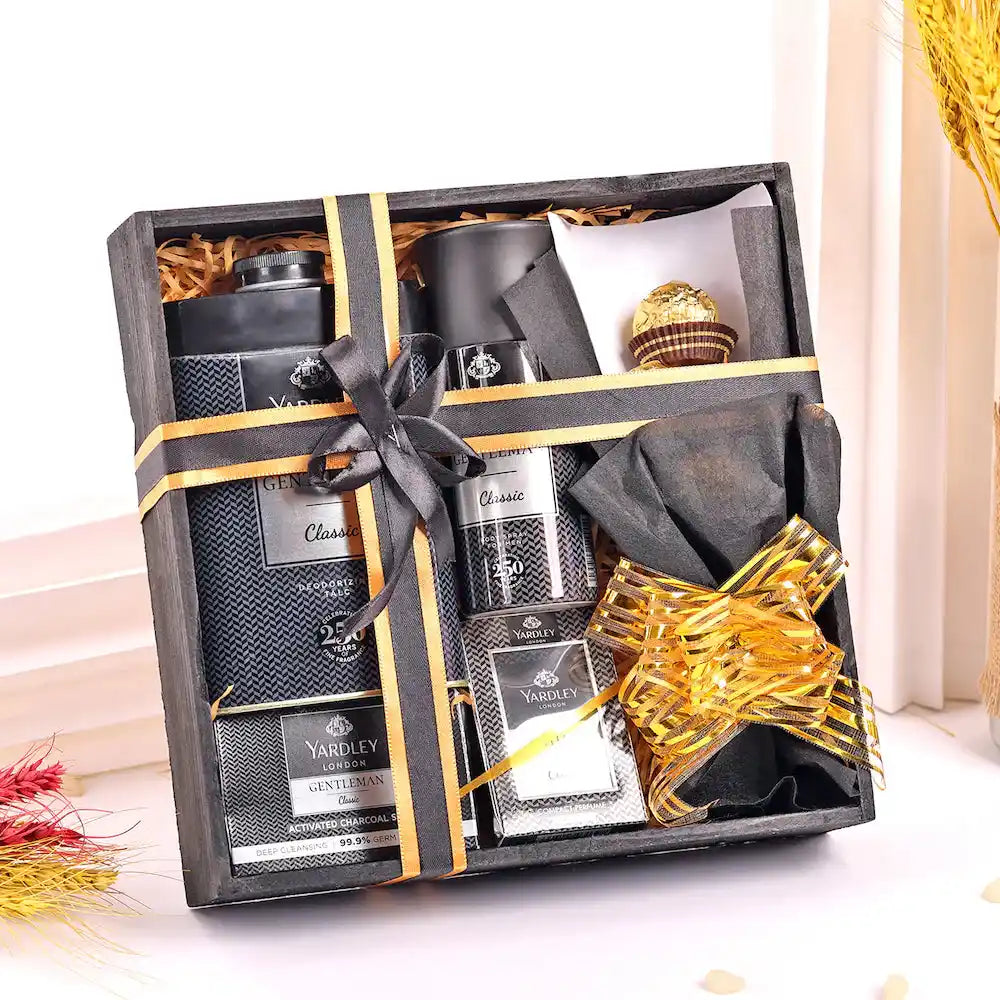 Stylish Yardley Black Kit for Men gift set with grooming products and chocolates in a black wooden box tied with gold ribbon.