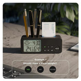 Black digital clock with pen holder and business card slot on a wooden surface