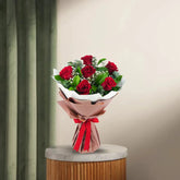 Charming 6 Red Roses Bouquet with lush green fillers wrapped in white and pink paper, ideal for romantic and anniversary gift occasions.