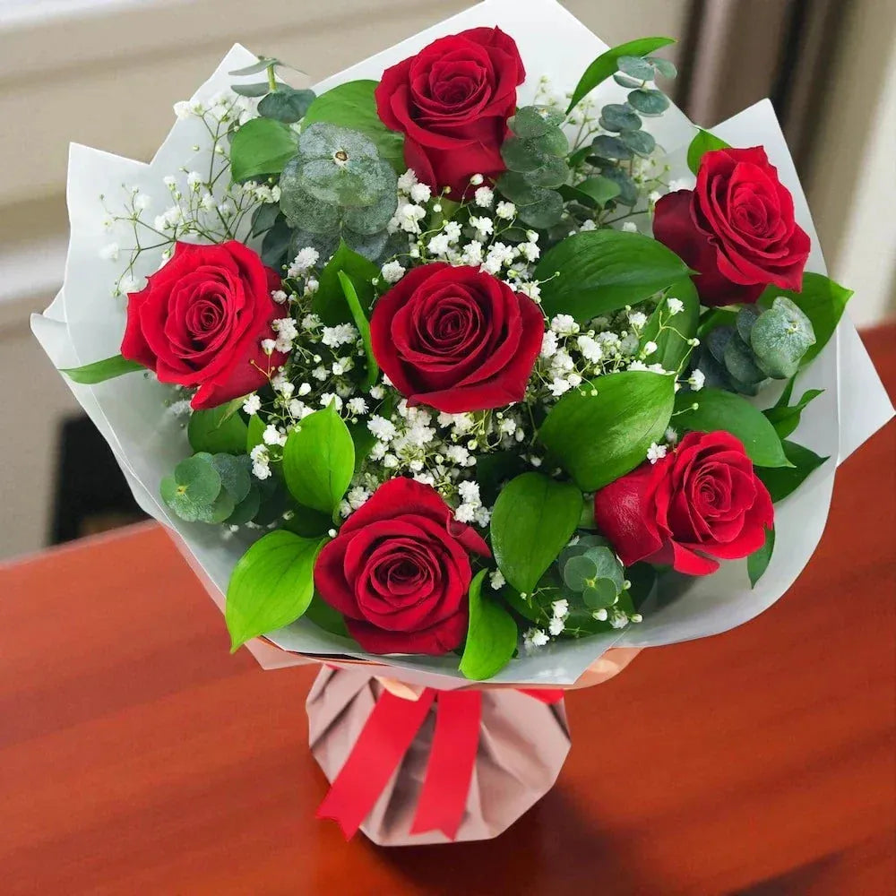 Elegant Charming 6 Red Roses Bouquet featuring vibrant red roses, baby's breath, and green foliage, perfect for anniversaries and birthday celebrations.