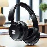 Black headphones with a brand logo on a desk in a bright room.