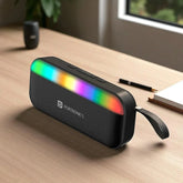 Black portable speaker with colorful LED lights on a wooden surface, featuring the Portronics brand.