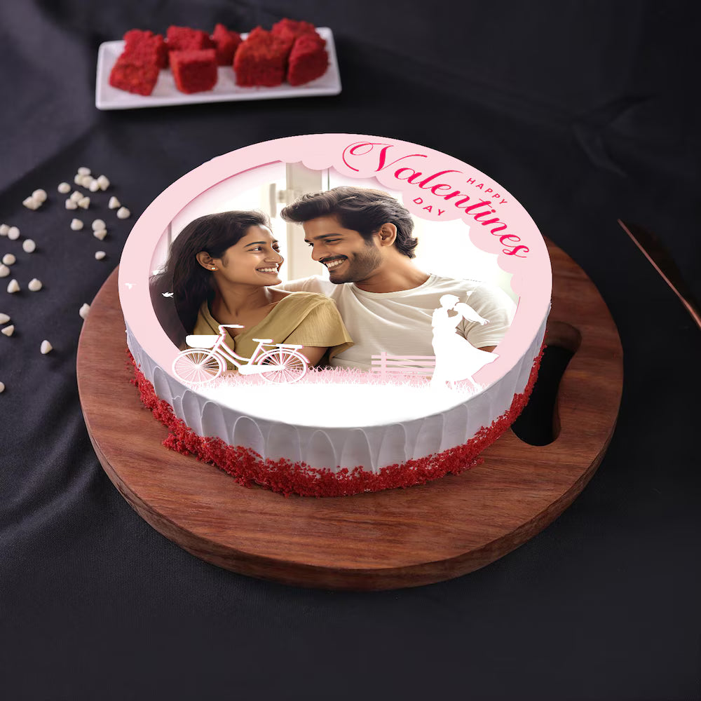 Round Valentine Red Velvet Photo Cake featuring heart-themed decor, vanilla filling, and custom couple image, ideal for Valentine's Day.