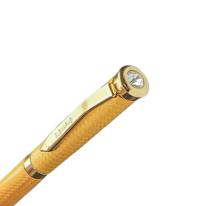 Gold pen with a textured grip and gemstone on a white background