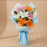 Bouquet of mixed Asiatic lilies with pink, white, and orange flowers wrapped in blue paper