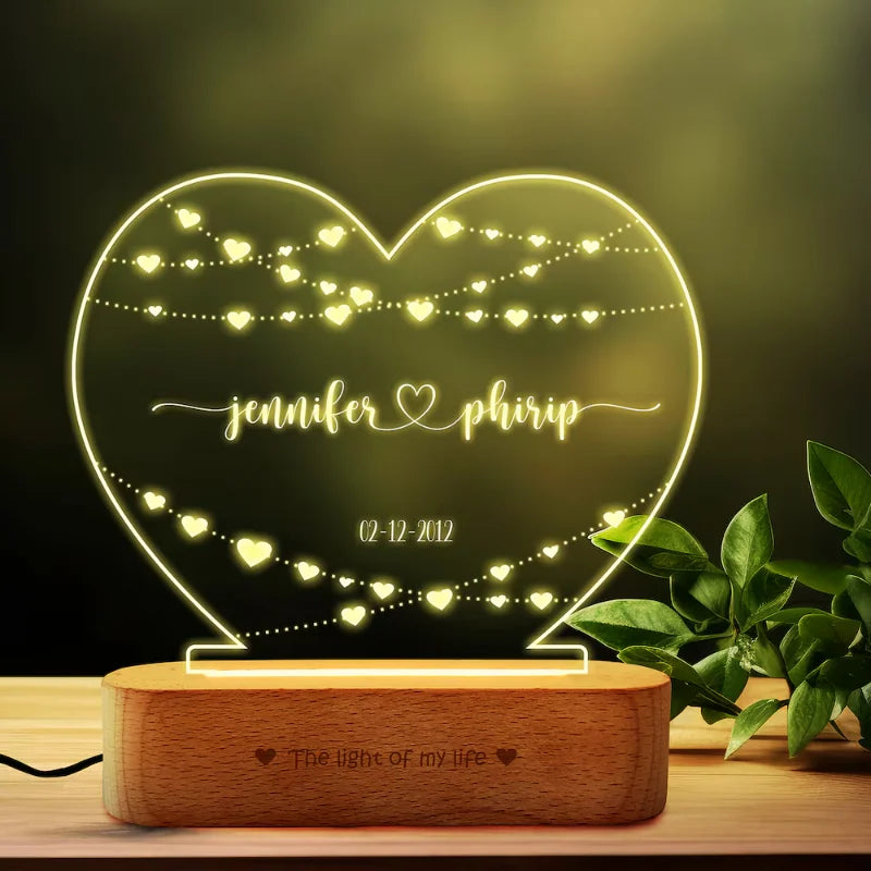 Illuminated Personalized Wedding Lamp glowing warmly, featuring engraved names and date on heart-shaped acrylic. Unique wedding or Valentine’s gift.