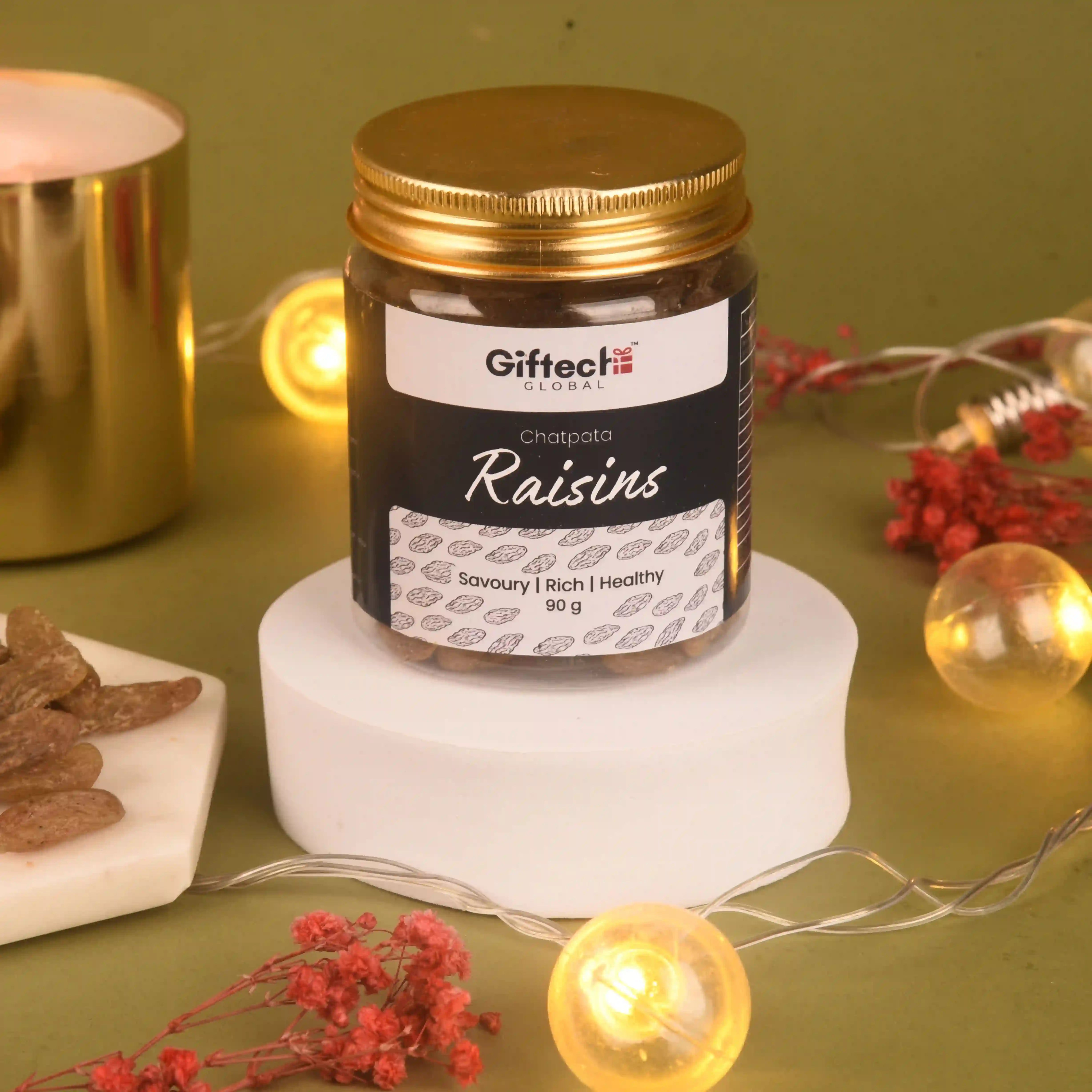 Jar of Giftech Raisins on a white stand with decorative lights and flowers on a green background