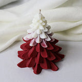 Tree-shaped candle with red and white gradient on a white fabric background