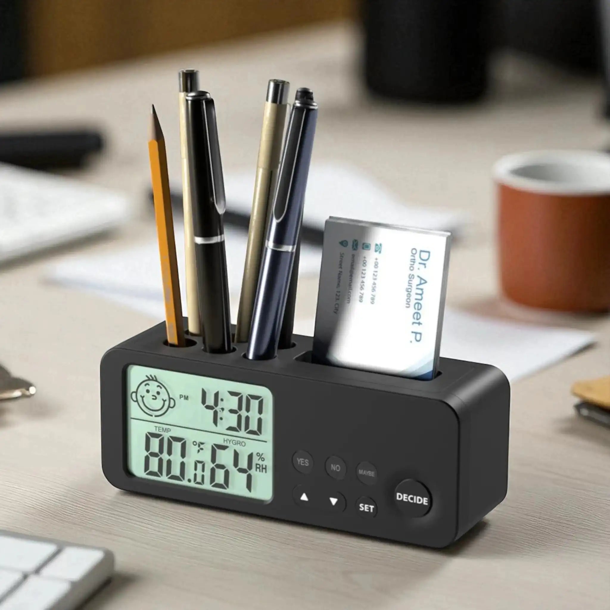 Black digital desk organizer with clock, pen holder, and card slot on a desk.