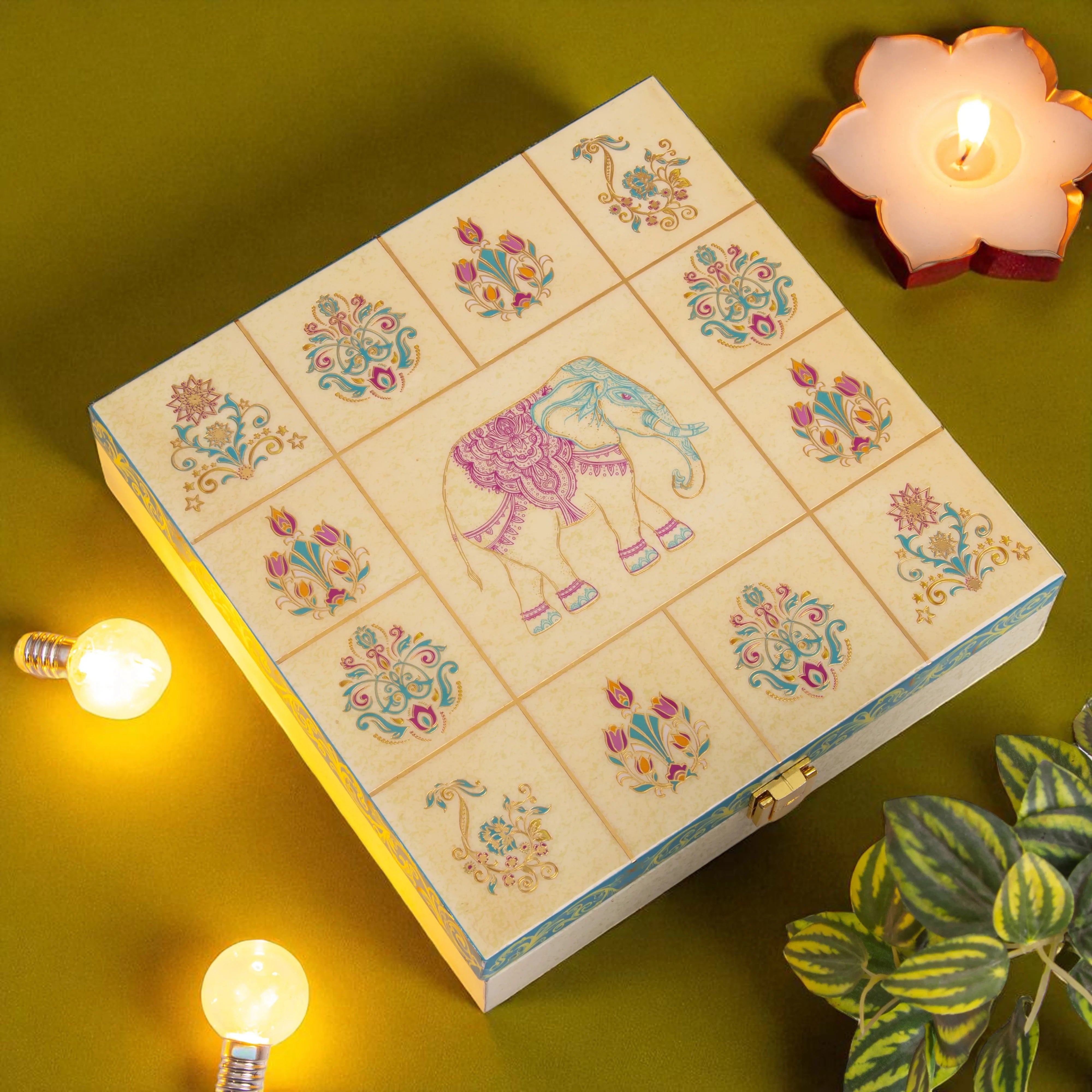Decorative box with floral and elephant design on a green background with candles and lights.
