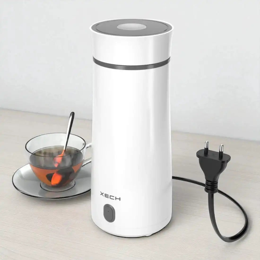 White electric kettle with power cord on a light wooden surface